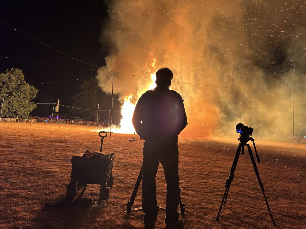 the silhouette of a man standing in front of a fire