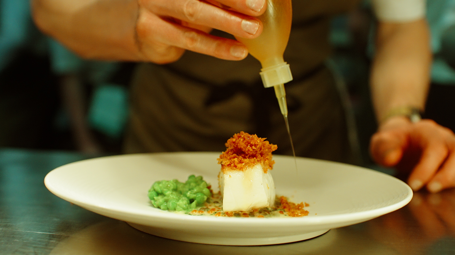 chef adding sauce to a dish