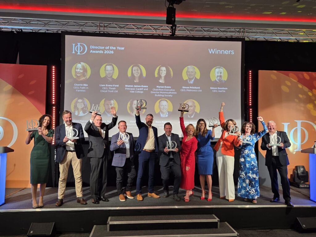 winners of the IOD Wales awards stand on stage with their trophies in the air